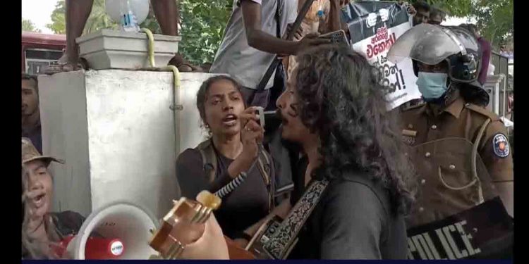 උස් හඬ නගව් රජ කලිසම් තෙමෙන්නට…! වස් කවි කියව් ලණු අමුඩෙත් හැලෙන්නට…! දහිරිය වඩව් යළි කලඑළි බසින්නට…! කළු කොඩි නගව් මිරිහානට පෙනෙන්නට..! අරගලකරුවන් මරදාන පොලිසිය ඉදිරිපිට සිංදු කියයි! (VIDEO)