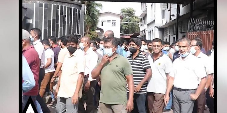 ආයතන ප්රධානීන්ගේ දීමනා එසේම තිබියදී සේවකයන්ගේ වැටුප් කප්පාදුව ඇරඹේ! විරෝධය පා මුද්රණ සේවකයෝ වැඩ නවත්වා පාරට බසිති! (VIDEO)