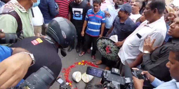 කංචනගේ තෙල් සංස්ථාව ඉදිරිපිට මළගෙයක් වගේ! සේවකයන් මළ බෙර ගහයි! මල්වඩම් අරන් ඇවිත් තියයි! පුහුල් කපයි! විකුණන කතාවට විරෝධය පළ කරයි! (VIDEO)